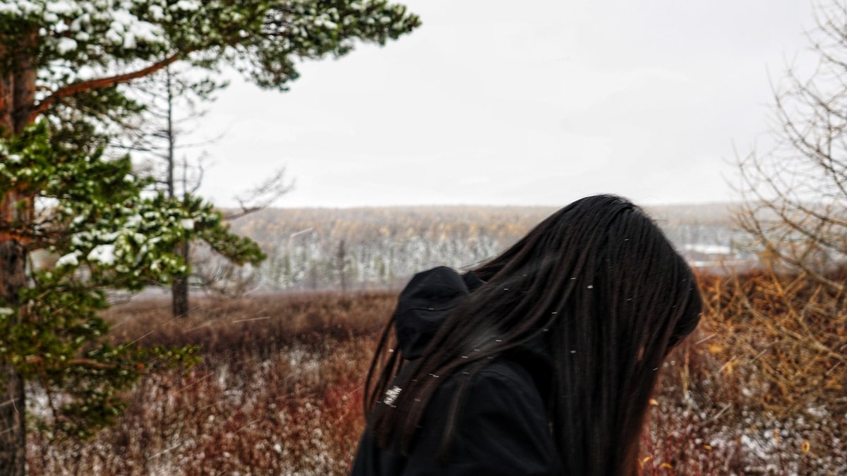 a woman with long hair standing in a field